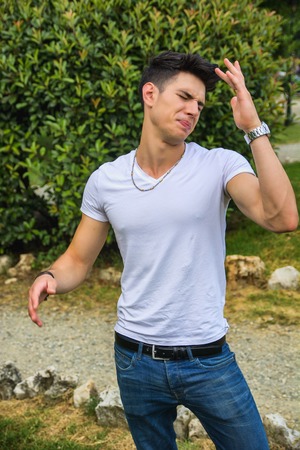 Three Quarter Shot of a Handsome Young Man Showing Disgusted Face Expression While at the Park.の写真素材