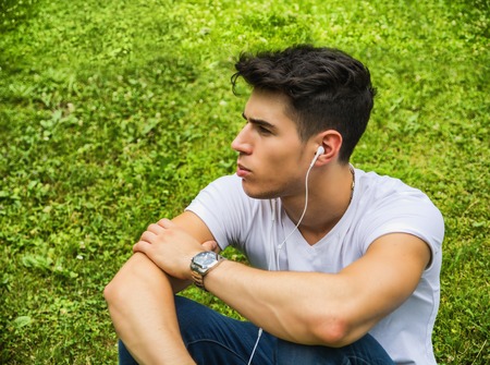Close up Young Man Listening to his Favorite Music Using Headphone at the Park, Using MP3 Playerの写真素材