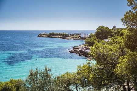 Overview of Isolated Deserted Sand Beach Along Rocky Cliff Lined Coast with Turquoise Waters on Coast of Ibiza, Spain on Sunny Day with Yachts in Distanceの写真素材