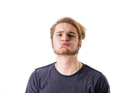Portrait of young man blowing lips while looking at camera. studio shot, isolated.の写真素材