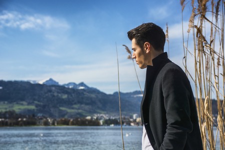 Handsome young man on Luzern lake's shore in a sunny, peaceful day, standing. Switzerland landscapeの写真素材