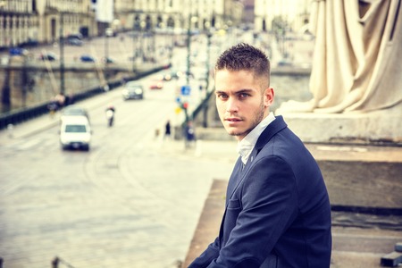 Handsome young man outdoor wearing jacket and shirt standing by historic building in European city. Turin, Italyの写真素材