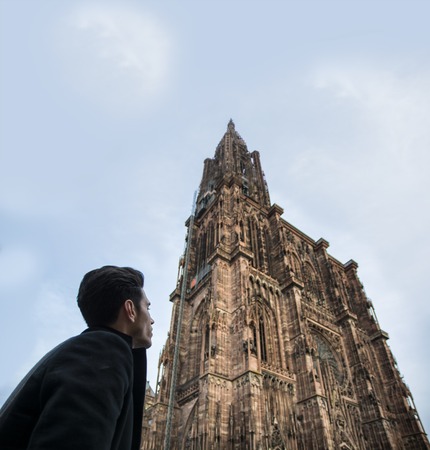 View on young man near Cathedral of Strasbourg in France with clear sky on backgroundの写真素材