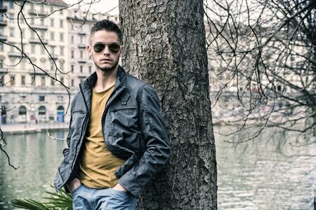 Three-quarter length of contemplative light brown haired young man wearing grey jacket and denim...