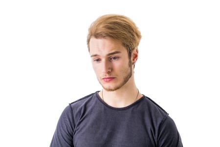 Sad or worried handsome young man looking down, isolated on white