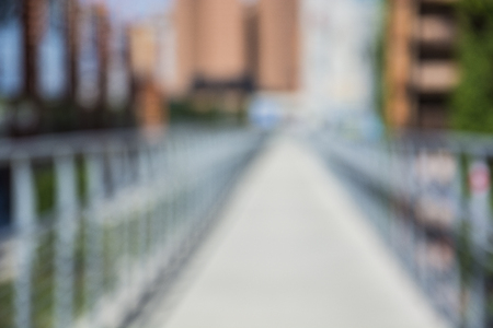 Unfocused blurred view on bridge and summer alley, in city setting. Urban environment backgroundの写真素材