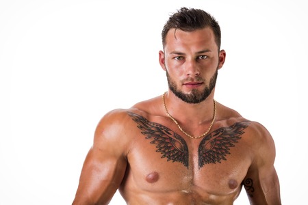 Muscular young man standing and looking at camera, shirtless, showing chiselled torso and pecs isolated on white in studio shotの写真素材