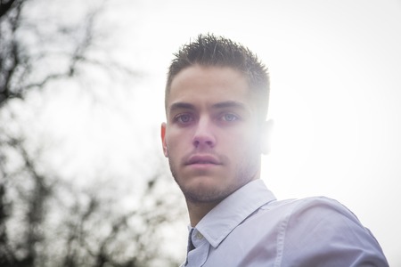Portrait of handsome young man looking to a side while sitting in city parkの写真素材