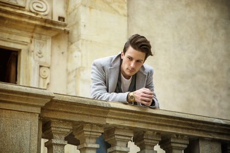 Elegant attractive young man outdoor wearing wool coat, in European city, looking away to a sideの写真素材