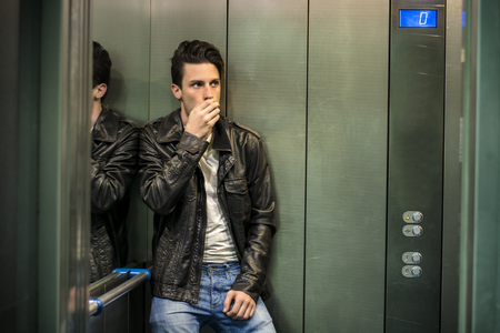 Scared young man desperate in stuck elevator screaming, looking very upset