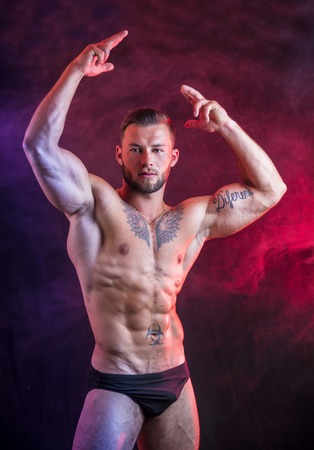 Handsome shirtless muscular man, standing, in studio shot