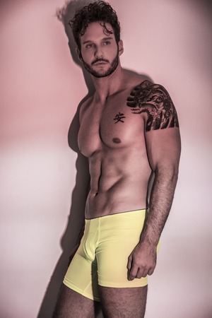 Handsome shirtless muscular man, standing, on light background in studio shotの写真素材