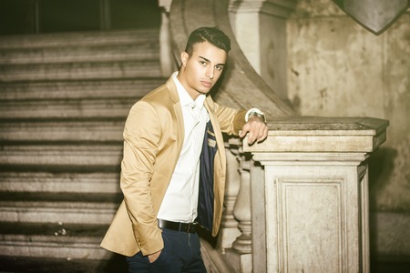 Elegant attractive young man outdoor wearing business suit, in European city on old stairs