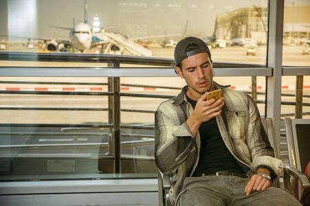 Portrait of a man in checkered shirt using cell phone at an airportの写真素材