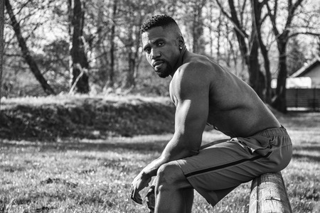 Muscular Shirtless Hunky Black Man Outdoor in City Park. Showing Healthy Muscle Body While Looking at Cameraの写真素材