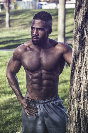 Muscular Shirtless Hunky Black Man Outdoor in City Park. Showing Healthy Muscle Body While Looking awayの写真素材