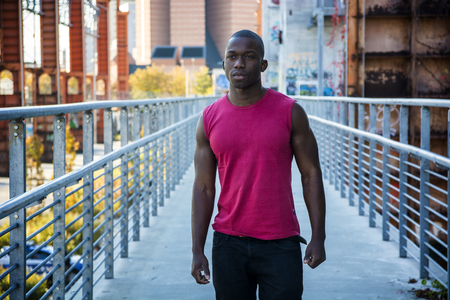 Portrait of a sexy young black man in urban environment wearing red sleeveless shirtの写真素材