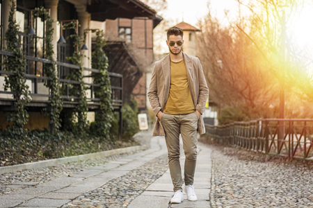 Handsome young man walking along rural road, looking confident and relaxedの写真素材
