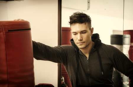 Handsome young man in gym next to punching bag, wearing training suitの写真素材