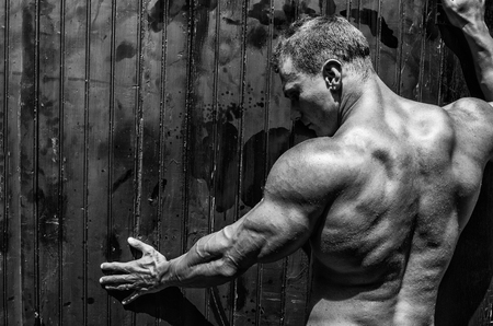 Handsome and muscular male bodybuilder against wooden wall, wearing only jeansの写真素材