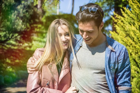 Boyfriend and girlfriend standing in countryside in green luscious field, strolling and cuddling, showing romantic loveの写真素材