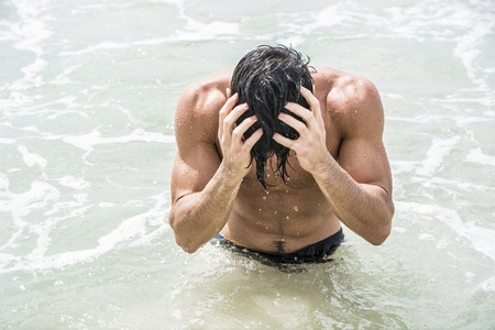 Handsome young man standing on a beach in Phuket Island, Thailand, shirtless wearing boxer shorts, showing muscular fit bodyの写真素材
