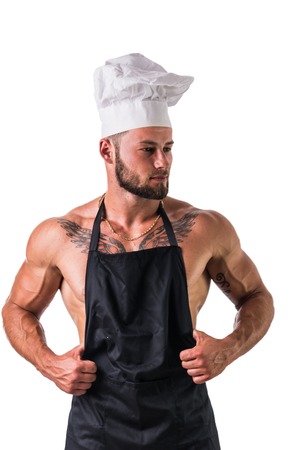 Male Bodybuilder Chef Wearing White Hat and Apron on Naked Muscular Body, While Looking to a Side. Isolated on White Background.の写真素材