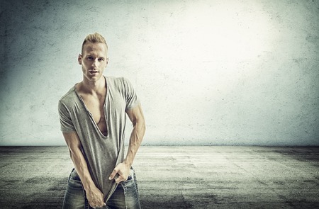 Muscular male model smiling, posing with a lot of confidence, in concrete roomの写真素材