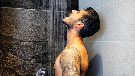 Close up of Attractive Young Bare Muscular Young Man with Tattoos Taking Showerの写真素材