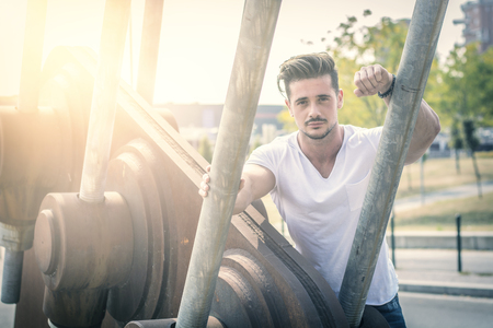 Attractive man in urban setting in front of big metal structureの写真素材