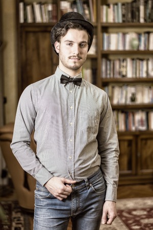 Attractive young man wearing top hat and bow tie, looking at camera. Indoors shotの写真素材