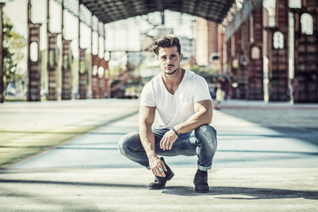Attractive man in urban setting under big metal structure, a former industrial siteの写真素材