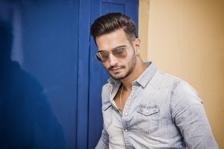 Attractive young man sitting against colorful wall, looking at cameraの写真素材