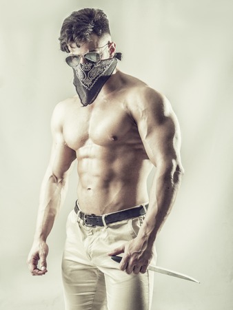 Handsome muscular young man with mask over face as a robber or banditの写真素材