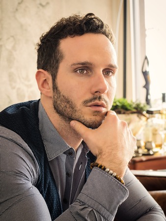 Handsome elegant man at home, wearing shirt and vest, looking away to a side