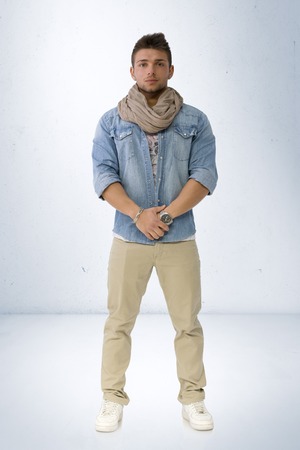 Handsome young man standing with denim shirt and scarf, full length body shotの写真素材