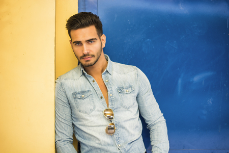 Attractive young man sitting against colorful wall, looking at cameraの写真素材