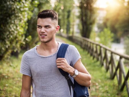 One handsome young man in urban setting in European city park, near a riverの写真素材