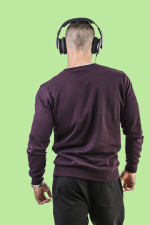 Rearview of man with headphones listening to music in studio shot