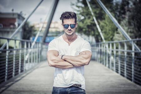 Handsome fit man in white t-shirt outdoor in city setting, looking at cameraの写真素材