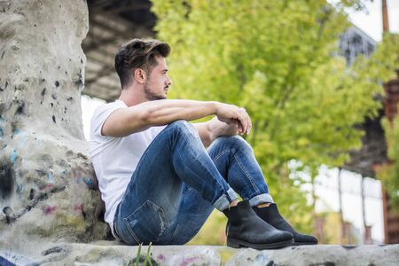 Handsome fit man in white t-shirt outdoor in city setting, looking awayの写真素材