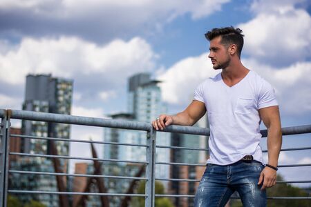 Handsome fit man in white t-shirt outdoor in city setting, looking awayの写真素材
