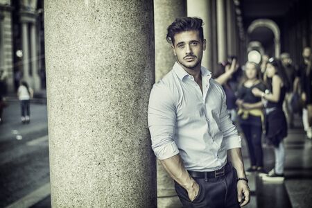 Stylish handsome man wearing elegant shirt, outside in urban setting, looking at cameraの写真素材