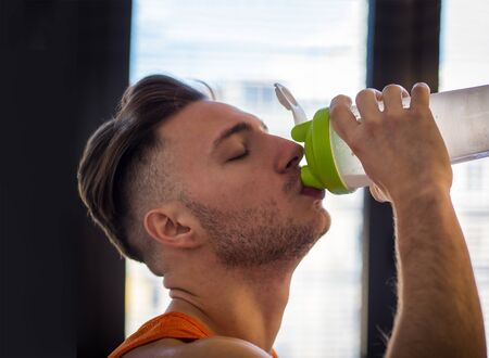 Young man drinking a healthy smoothie drink or a protein shake from blender or shakerの写真素材