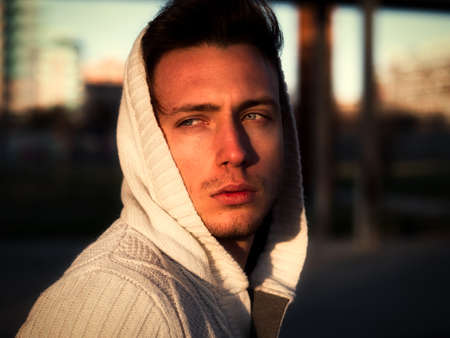 Handsome young man in black hoodie sweater standing outdoor in street