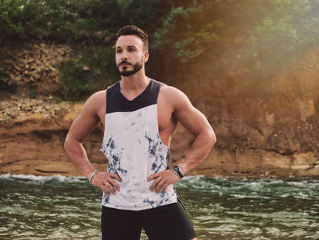 Handsome athletic young man near river, standingの写真素材