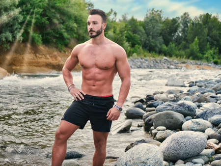 Handsome young muscular man in water pond, shirtlessの写真素材