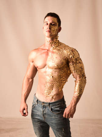 Muscular young man covered with golden specksの写真素材