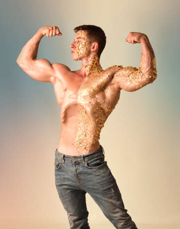 Muscular young man covered with golden specksの写真素材