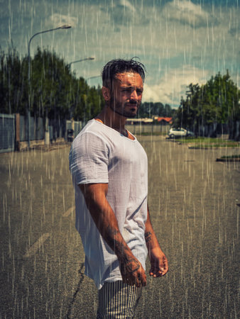 Handsome athletic fit young man under rain on city streetの写真素材